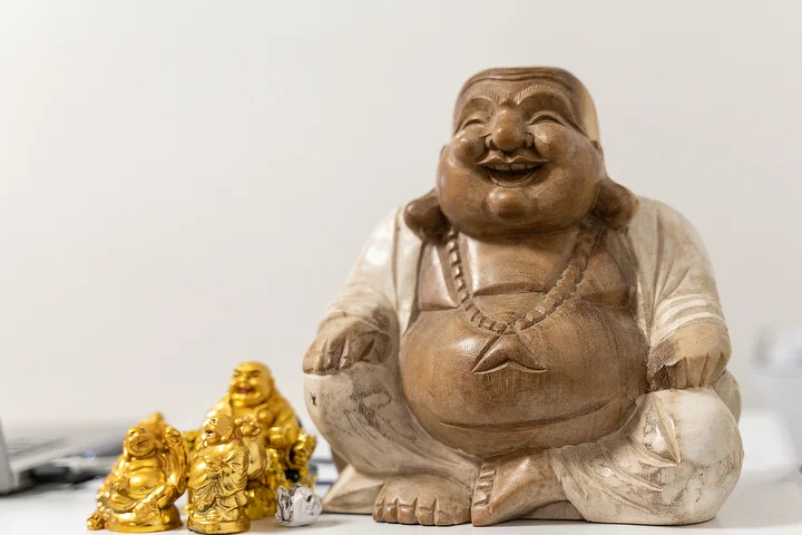 A carved wooden laughing Buddha with small gold figures